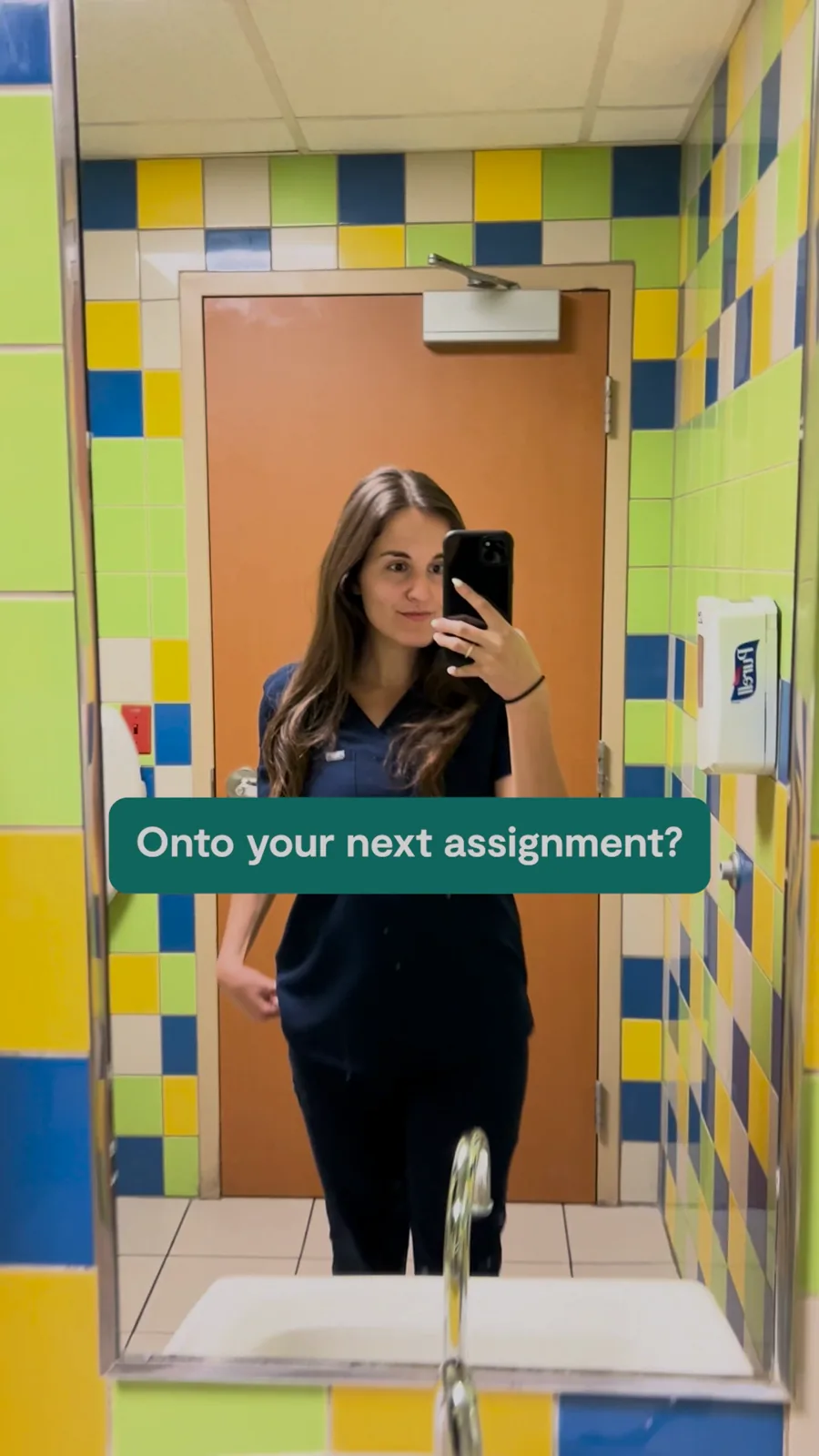 A tall video still: a nurse in scrubs takes a mirror selfie in a tiled hospital restroom, a green caption asking "Onto your next assignment?"