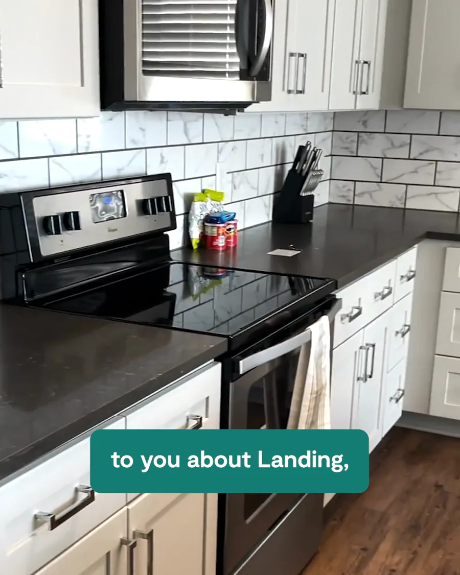 A video still: a clean apartment kitchen with a stove and white cabinets, a green caption bar running across the counter.