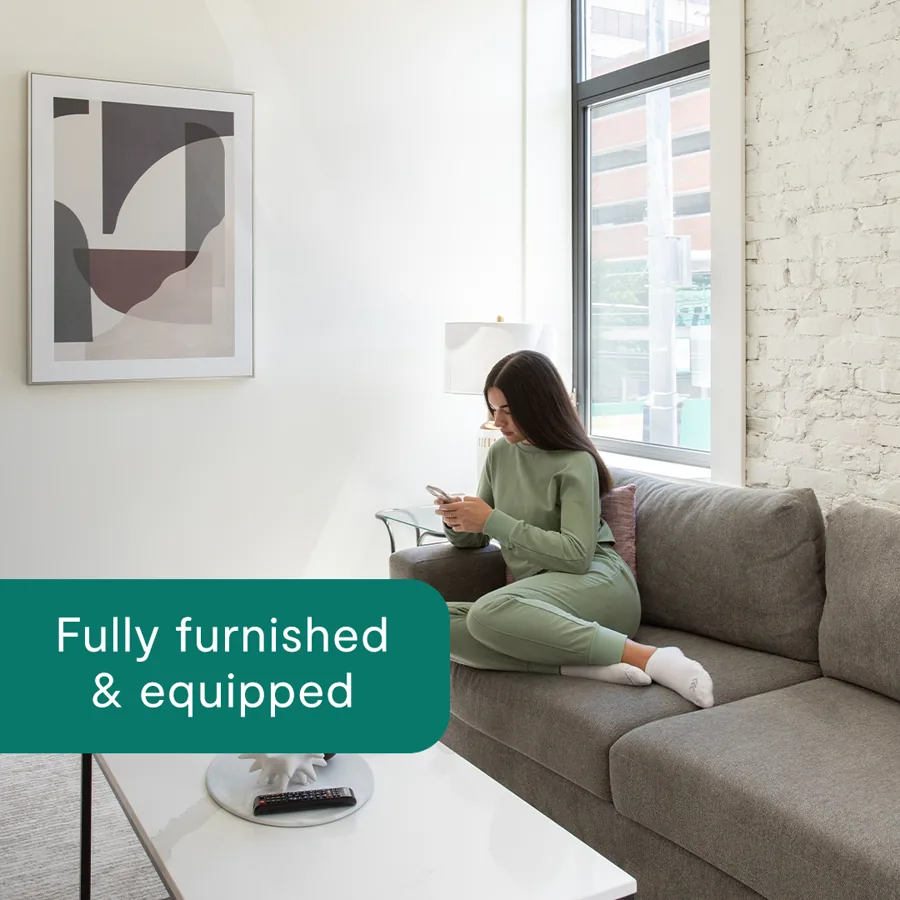 A square ad: a woman in green loungewear on a sofa with her phone in a bright flat, a green tab reading "Fully furnished and equipped".