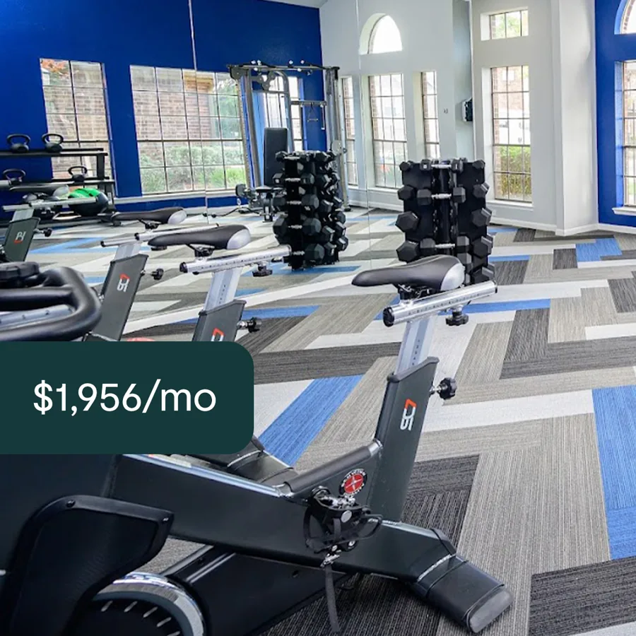 A square ad: a residents' gym with exercise bikes and dumbbell racks on blue and grey carpet, a dark tab with the monthly rent.