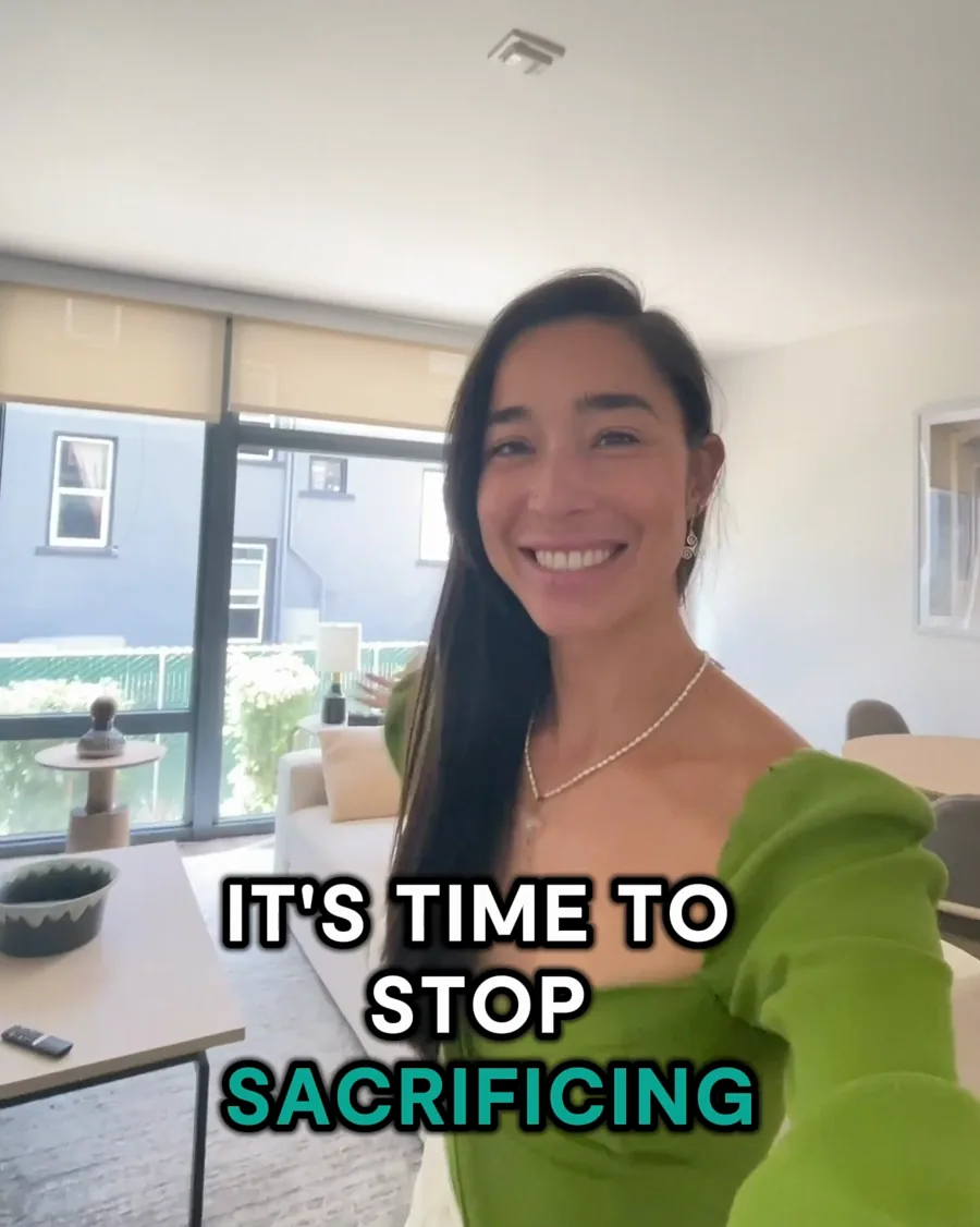 A video still: a smiling woman in a green top films herself in a bright apartment, bold captions reading "It's time to stop sacrificing".