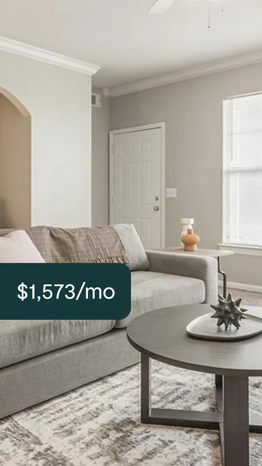 A tall ad: a grey sofa and a round coffee table in a calm living room, a dark tab with the monthly rent.