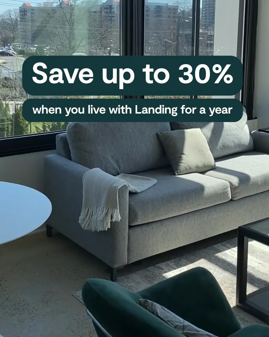 A video still: a grey sofa by sunny windows over a city, a dark caption reading "Save up to 30%" and a line about living with the brand for a year.